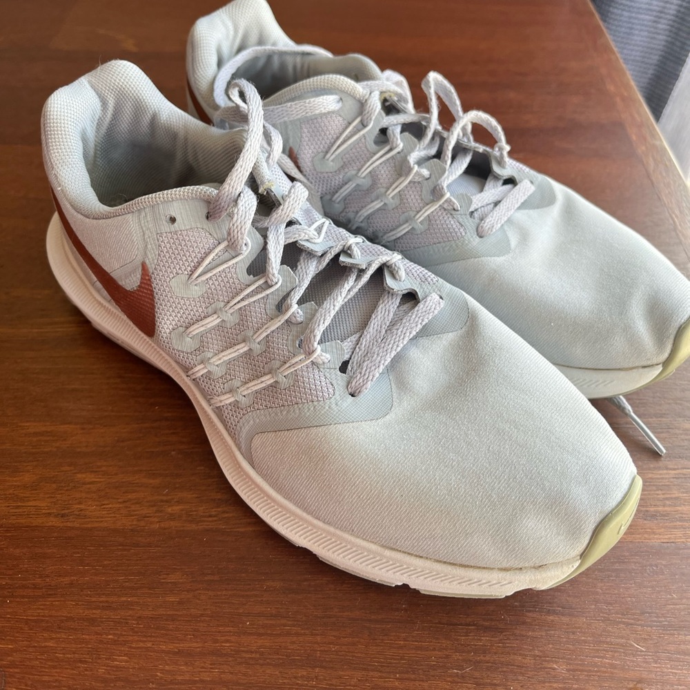 Nike running shoes with rose gold logo